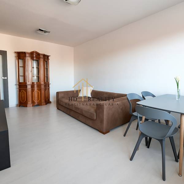 Nappali kanapéval és vitrinnel, fa hatású padlóval egy háromszobás lakásban.