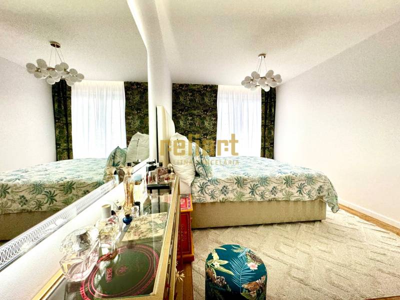 Hálószoba egy 3 szobás lakásban elegáns tükörrel és virágmintával.