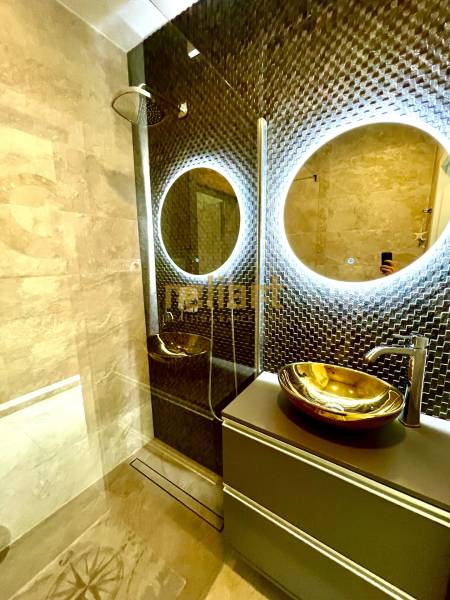 Luxusos fürdőszoba LED tükörrel és arany mosdótállal egy háromszobás lakásban.