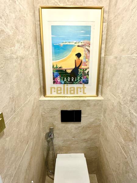 Háromszobás lakás WC-je, WC fölött egy képpel és csempével.