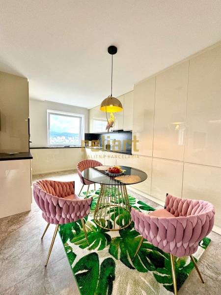 Étkező sarok üveg asztallal és rózsaszín székekkel egy háromszobás lakásban.