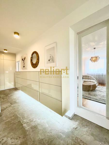 Folyosó egy 3 szobás lakásban csempézett padlóval, dekoratív képekkel és tükörrel.