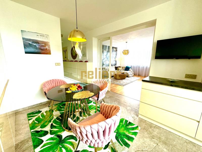 Étkező sarok kerek asztallal, székekkel és televízióval egy háromszobás lakásban.