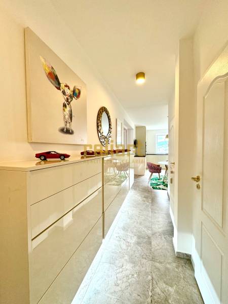 3 szobás lakás belső tere világos folyosóval, művészettel és bútorokkal.