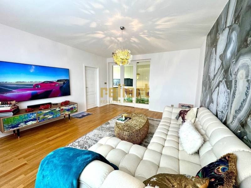 Nappali egy háromszobás lakásban, stílusos ülőgarnitúrával és falra szerelt televízióval.