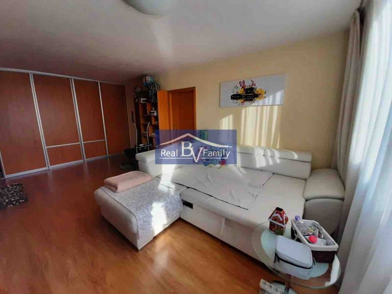 Világos nappali egy kétszobás lakásban, fa dekor padlóval és fehér kanapéval.