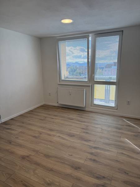 Garzonlakás fa dekor padlóval és nagy ablakkal, amely kilátást nyújt a környékre.