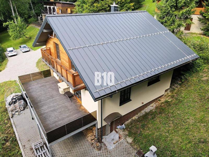 Házikó Terchovában ferde tetővel, nagy terasszal és fa részletekkel.