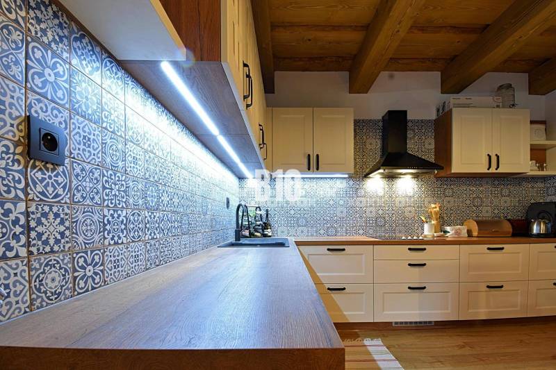 Konyha a házban csempézett falakkal és fa dekorációjú padlóval, LED világítással megvilágítva.