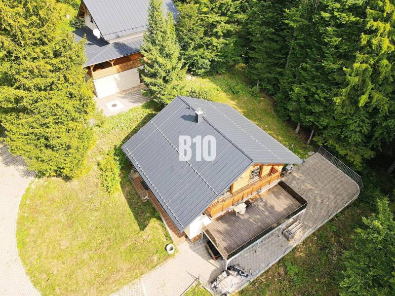 Házikó Terchován, erdővel körülvéve, fa terasszal és szomszédos kerttel.