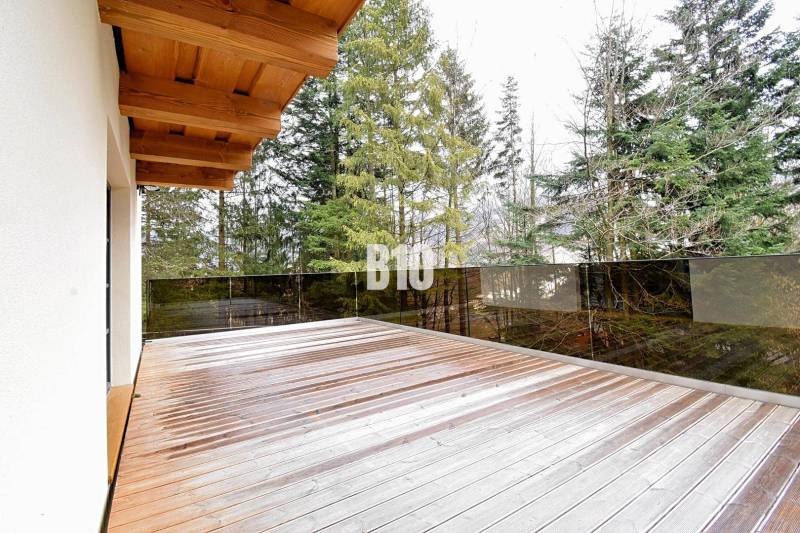 Terchován található egy faház terasszal és fa dekorációjú padlóval, erdővel körülvéve.