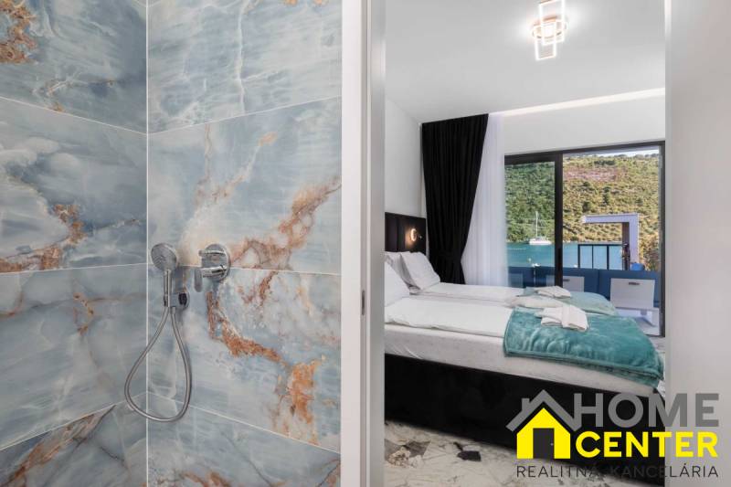 Fürdőszoba márványburkolattal és hálószoba egy villában tengerre néző kilátással.