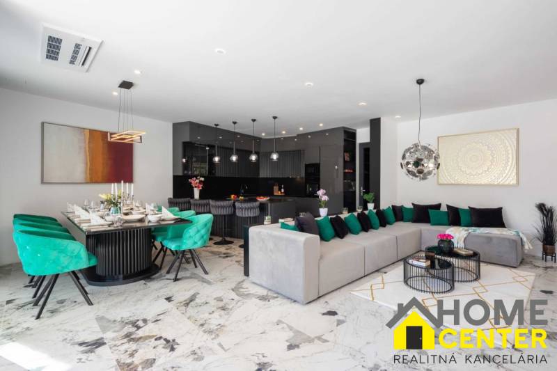 Tágas nappali a villában étkezővel, kanapéval és modern konyhával.