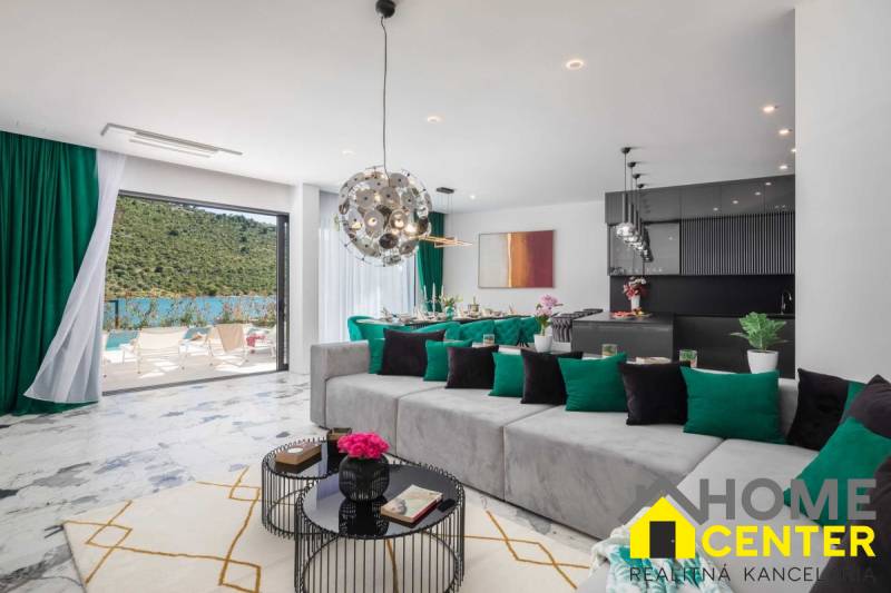 Tágas nappali a villában, kilátással a medencére és a természeti környezetre.