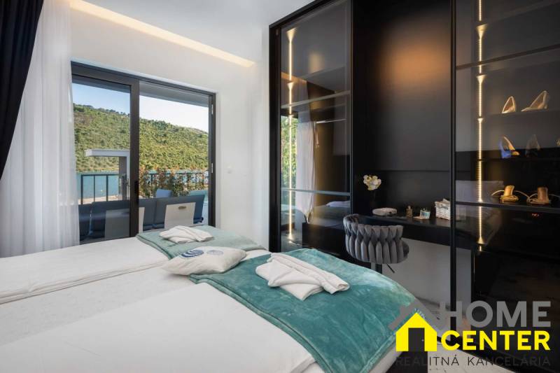 Hálószoba villában terasszal, kilátással a természetre és a tóra.