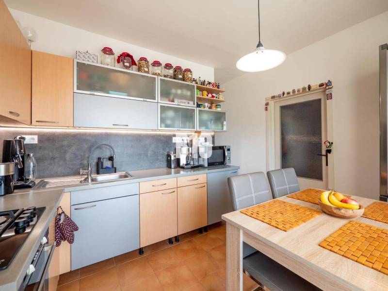 Konyha egy 4 szobás lakásban számítógéppel és fa dekorú konyhabútorral.