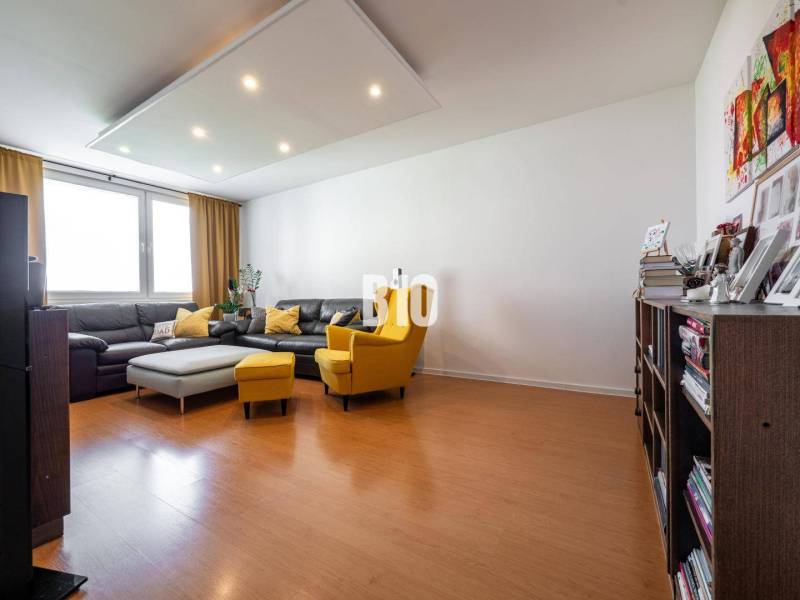 Nappali egy négy szobás lakásban, fa dekoros padlóval és kényelmes bútorokkal.