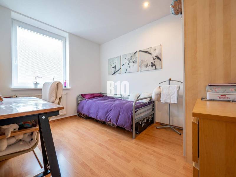 Hálószoba egy 4 szobás lakásban, fa dekorációjú padlóval és lila ágytakaróval.