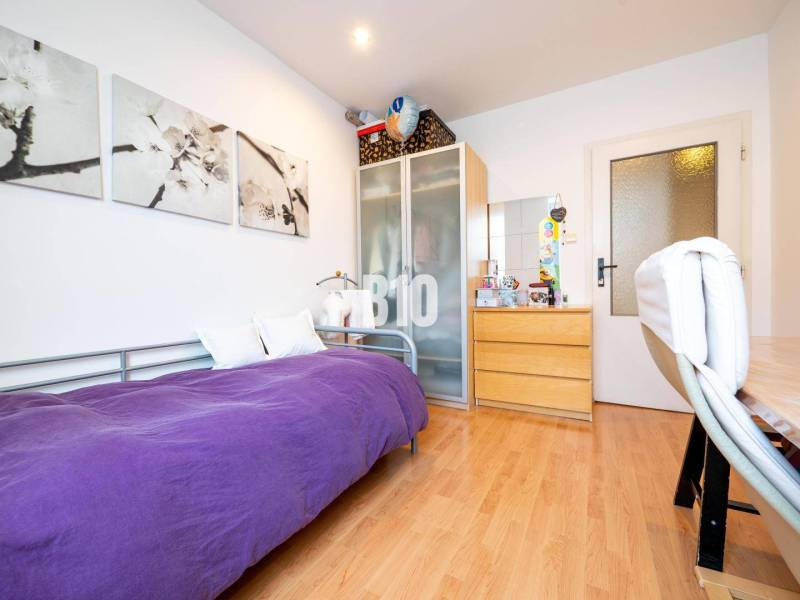 Szoba egy négyszobás lakásban egyszemélyes ággyal, szekrénnyel és fa mintázatú padlóval.