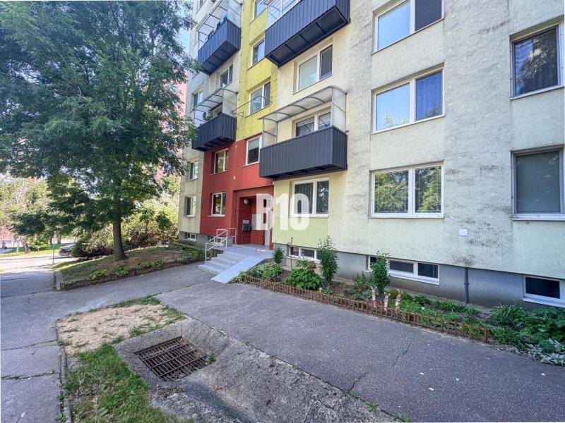 Nyitrán található egy lakóház érdekes színű homlokzattal, zöldterület közelében.