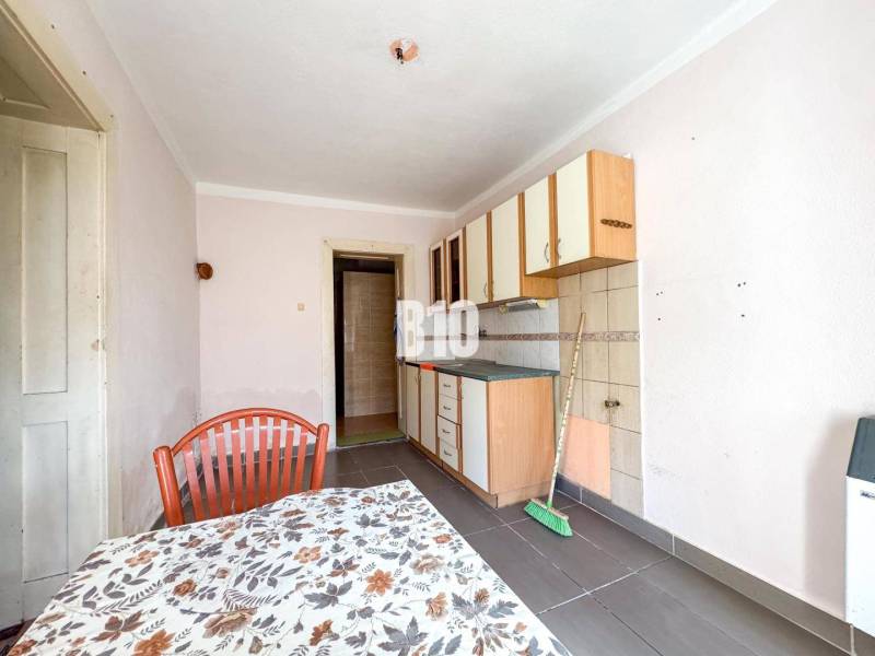 Konyha egyszerű szekrényekkel, csempékkel és asztallal egy családi házban.