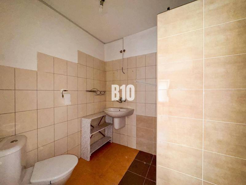 Fürdőszoba egy családi házban bézs csempével és fehér szaniter berendezésekkel.