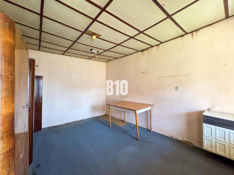 Egy családi ház szobájának belseje, amely tartalmaz szőnyeget, szekrényeket és egy asztalt.