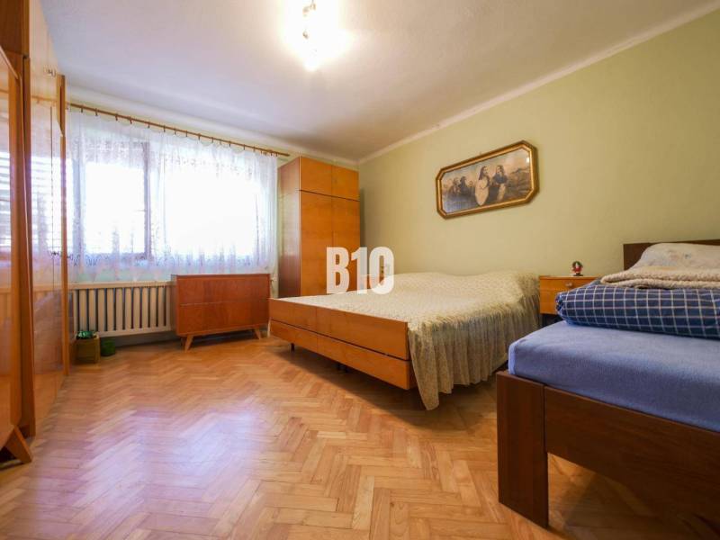 Hálószoba fa padlóval és egyszerű bútorokkal egy családi házban.