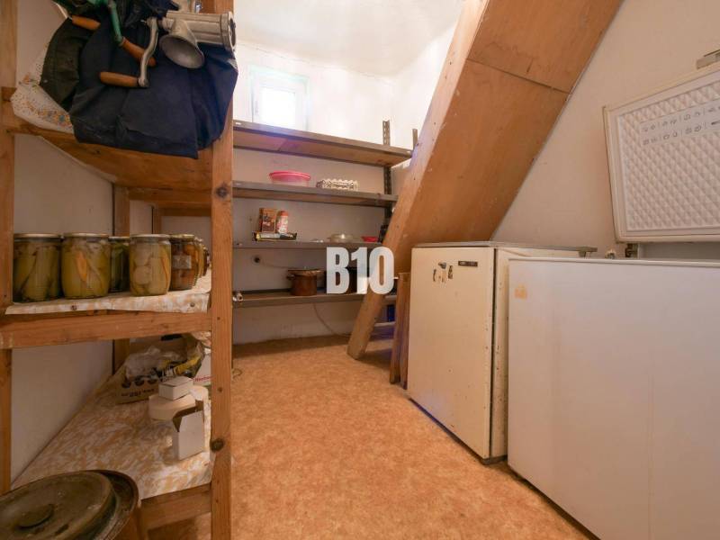 Spájz a családi házban polcokkal, konzervdobozokkal és egy régebbi hűtőszekrénnyel.