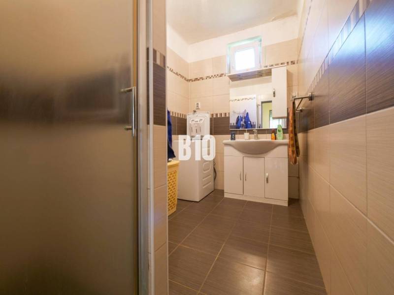 Fürdőszoba egy családi házban mosógéppel és mosdóval, barna csempével burkolva.