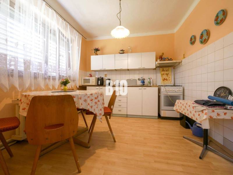 Családi ház konyhája étkezőasztallal, konyhabútorral és háztartási gépekkel.