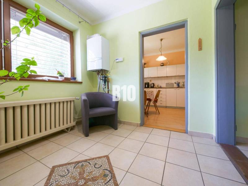 Családi ház belső tere előszobával, növénnyel, székkel és kilátással a konyhára.