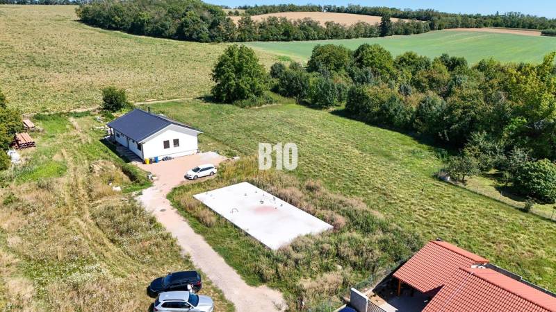 Telek kilátás lakóhely céljára Csallóközben, amely magában foglalja a házat, a zöldterületet és az autókat.