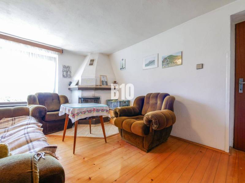 Családi ház kandallóval, kényelmes fotelekkel és fa dekorációjú padlóval.