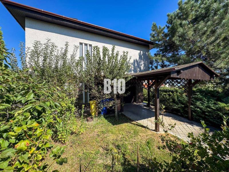 Családi ház a Nyitrai Kő utcában, zölddel körülvéve és autóbeállóval.