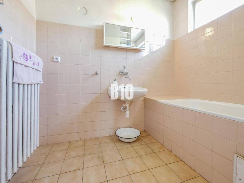 Fürdőszoba családi házban káddal és világos burkolatokkal a falakon.