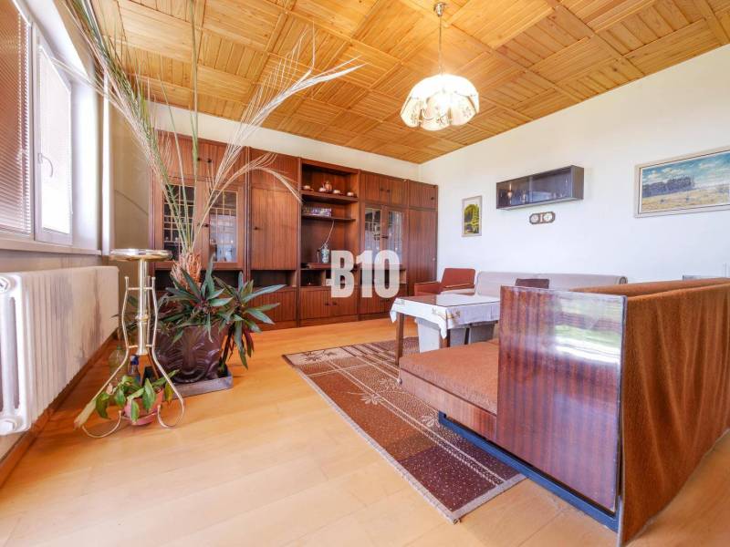 Nappali egy családi házban, fa mintázatú padlóval és fa mennyezettel.