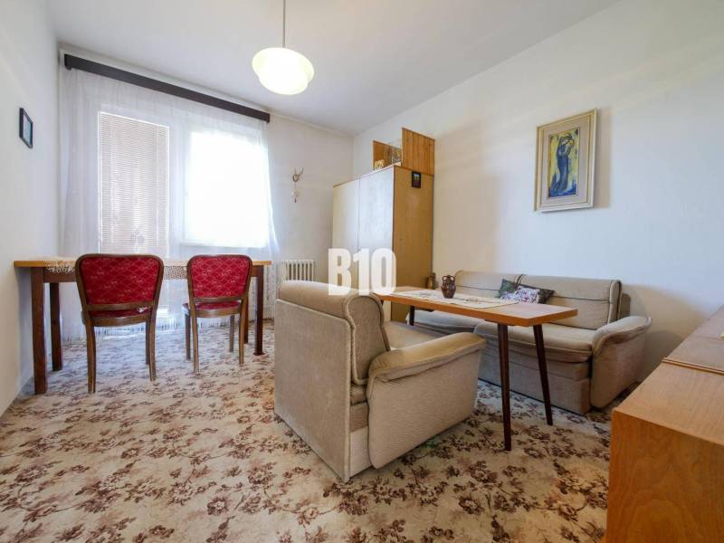 Nappali egy családi házban szőnyeggel és piros székekkel.