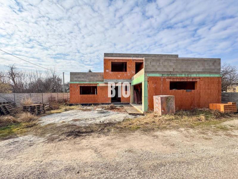 Befejezetlen téglából épült családi ház csendes környezetben, ideális a leendő tulajdonosok számára.