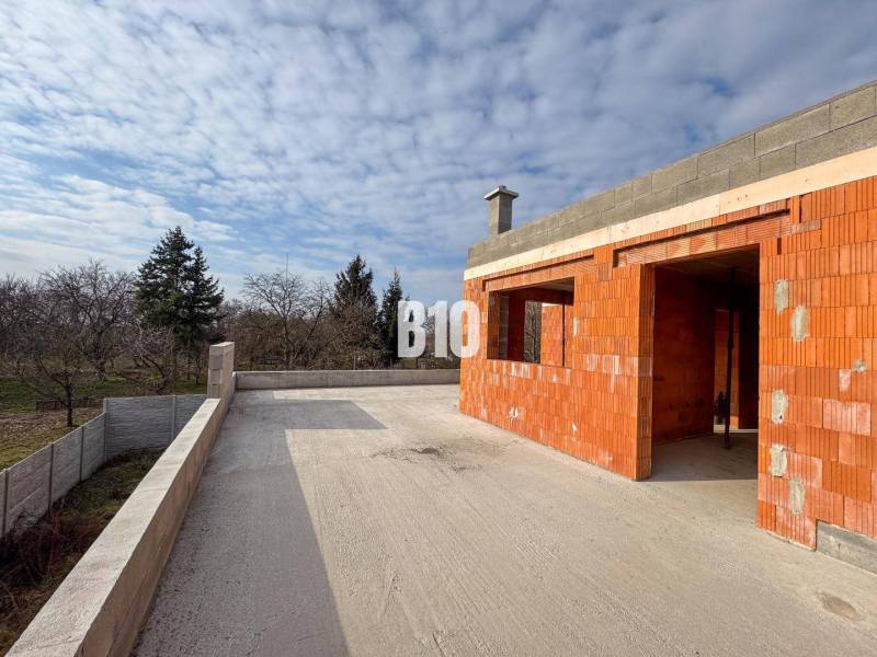 Építés alatt álló családi ház terasszal a nagy udvaron, természet és fák ölelésében.