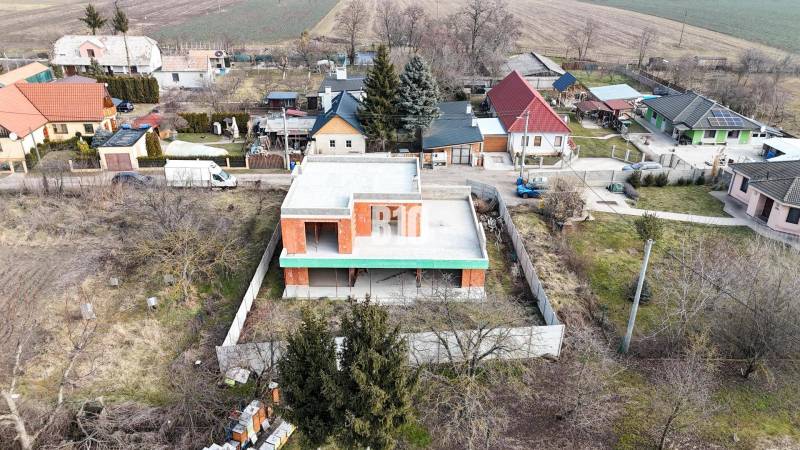 Családi ház építése garázzsal kellemes vidéki környezetben, családi házak között.