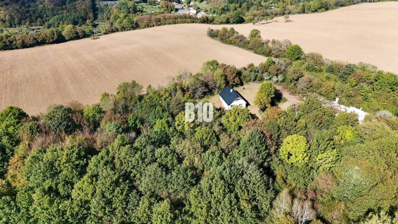 Ház Lackovban, erdővel és mezőkkel körülvéve, nyugodt vidéki táj.