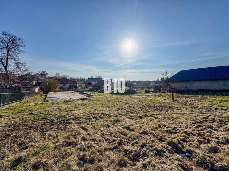 Telek betonalappal készen áll a lakhatásra, napos időjárás és környező táj.