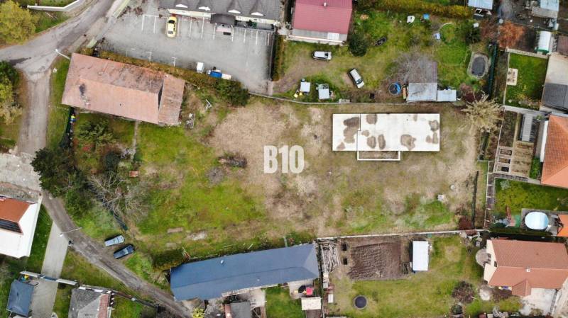 Légi felvétel egy telekről, épülettel és parkolóhelyekkel, ideális lakhatásra.
