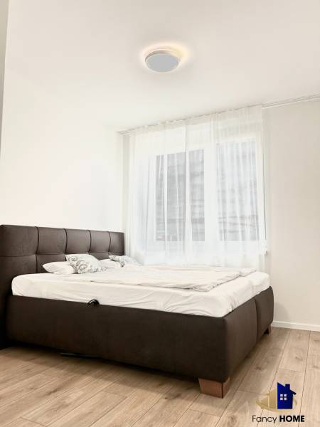 Hálószoba egy kétszobás lakásban, fa dekor padlóval és kényelmes ággyal.