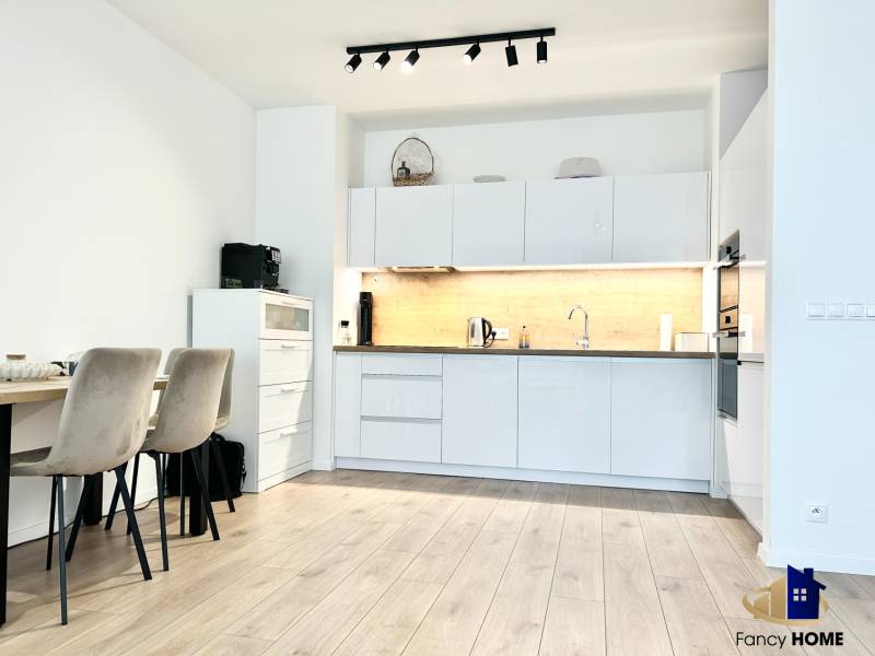 Konyha egy kétszobás lakásban, fa dekoros padlóval és étkezőasztallal.