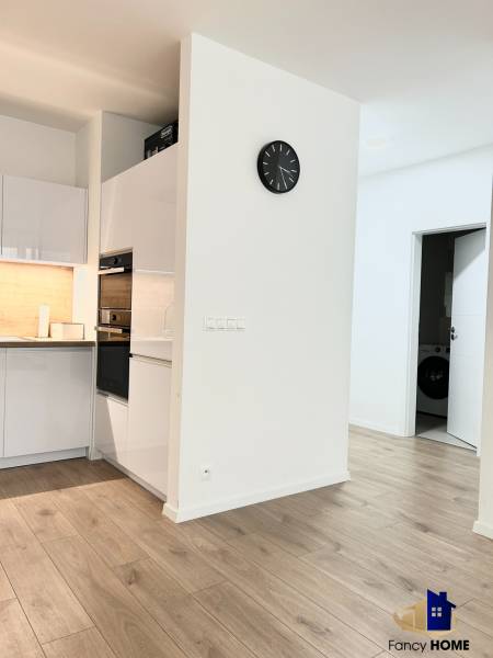 Konyha egy kétszobás lakásban, fa dekor padlóval és fehér bútorokkal.