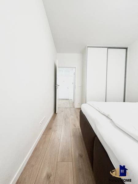 Szoba egy kétszobás lakásban, fa dekorációjú padlóval és beépített szekrénnyel.