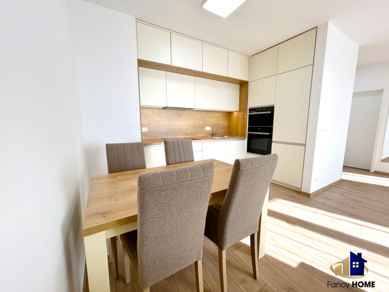 Konyha egy kétszobás lakásban étkezőasztallal és székekkel, fa mintázatú padlóval.