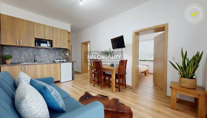 Nappali egy háromszobás lakásban, fa hatású padlóval és kényelmes ülőgarnitúrával.